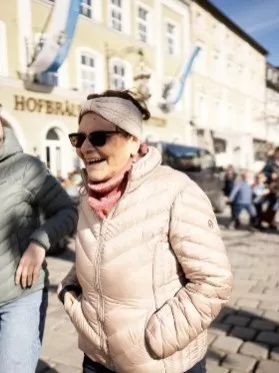Eine Frau sitzt im Garten und hält ein Foto in den Händen.