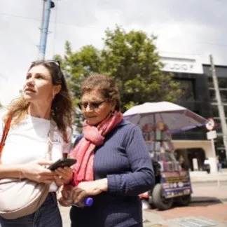 Zwei Frauen gehen nebeneinander durch eine Innenstadt.